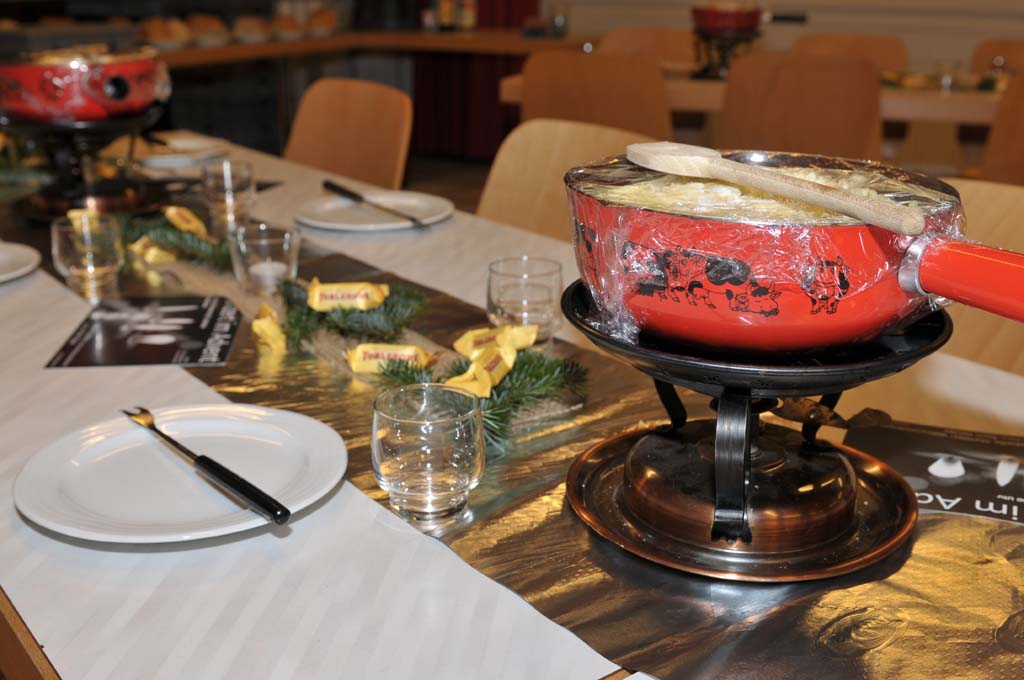 Fonduecaquelon steht auf leerem Tisch bereit.