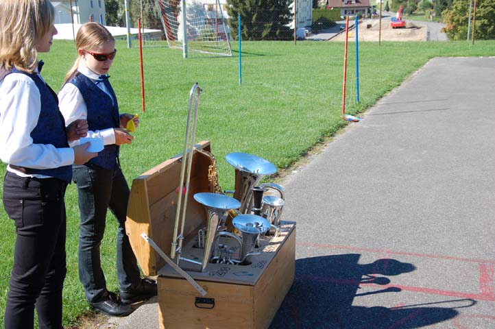 Zwei Jugendliche hinter einer Truhe mit Instrumenten auf dem Schulhausplatz.