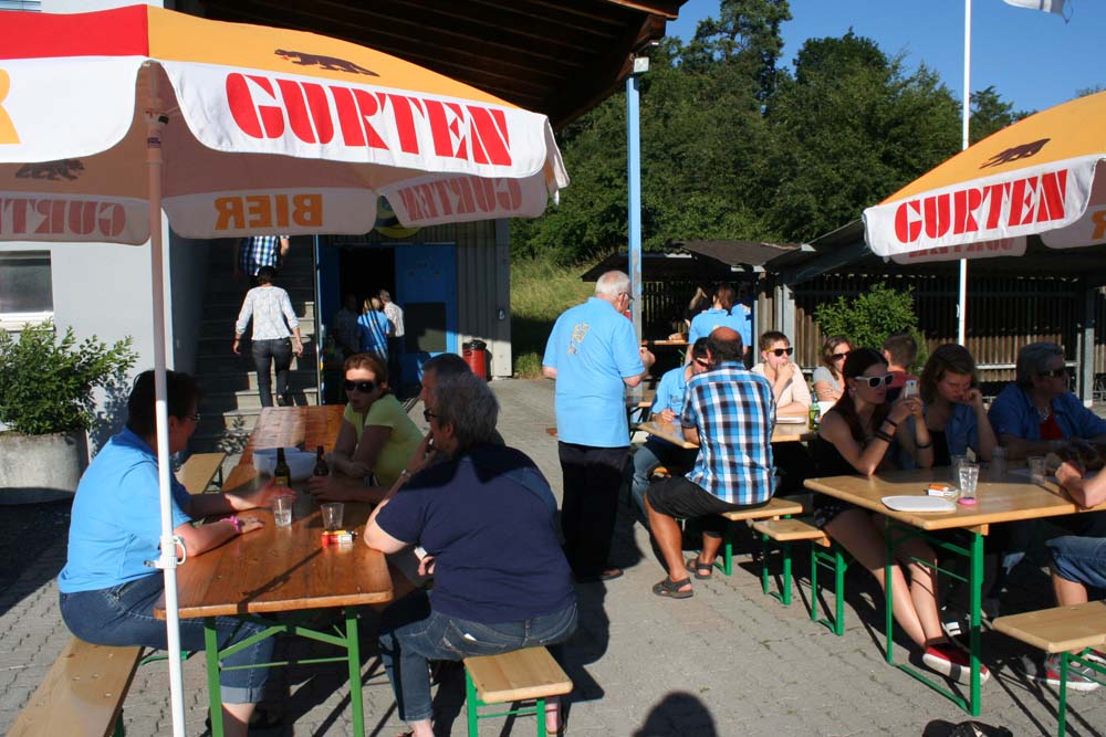 Personen an Festtischen unter Gurten Bier Sonnenschirmen.