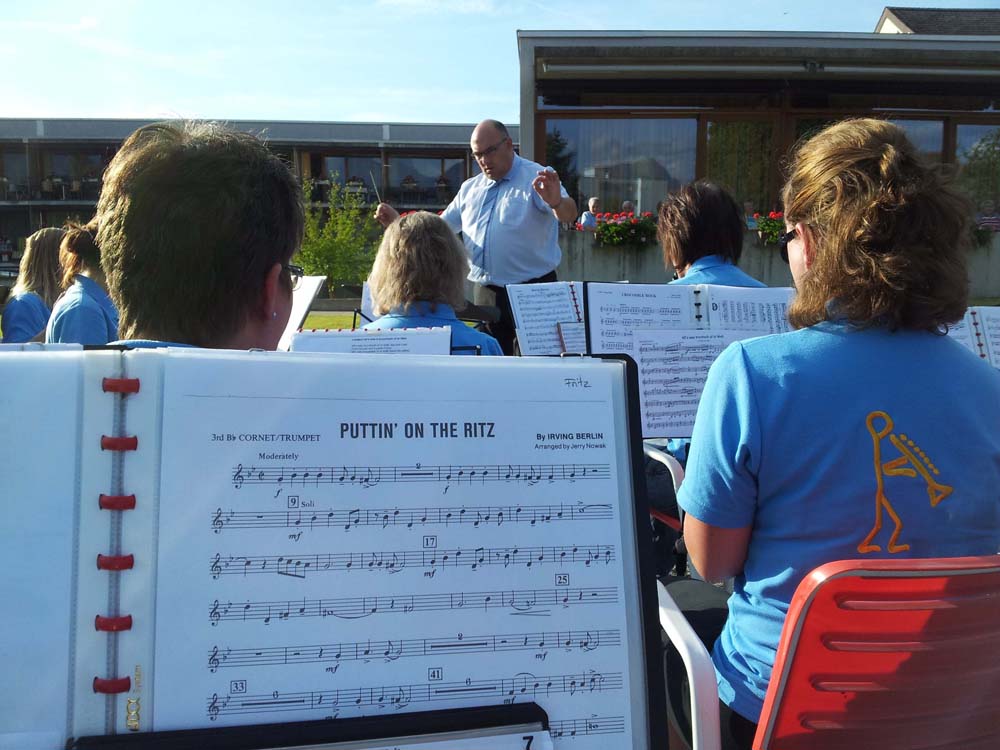 Noten "Puttin' on the Ritz" auf einem Notenständer. Dahinter waltet der Dirigent seines Amtes.