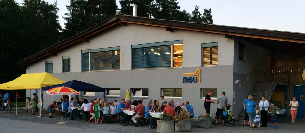 Unser Probelokal von aussen. Davor farbige Zelte und Sonnenschirme sowie Festbänke.