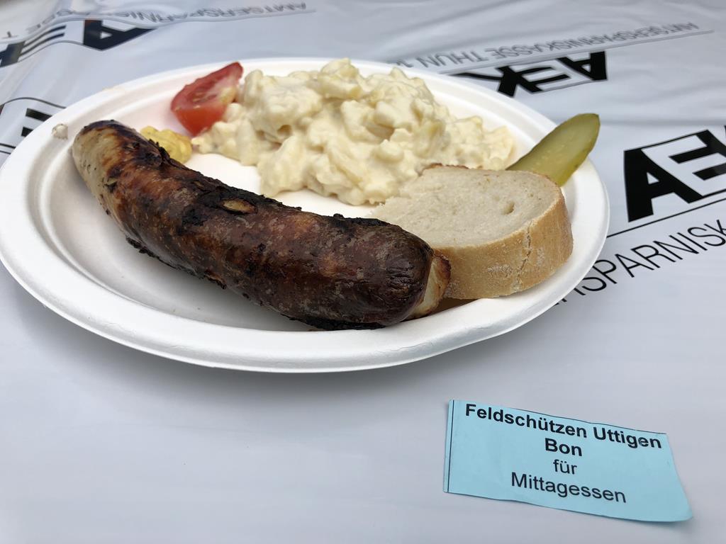 Wurst mit Brot und Kartoffensalat auf Teller.